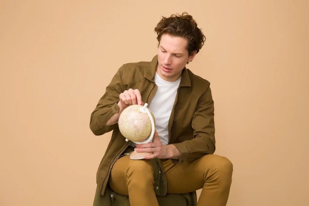 In the picture, a man sits looking at a globe.